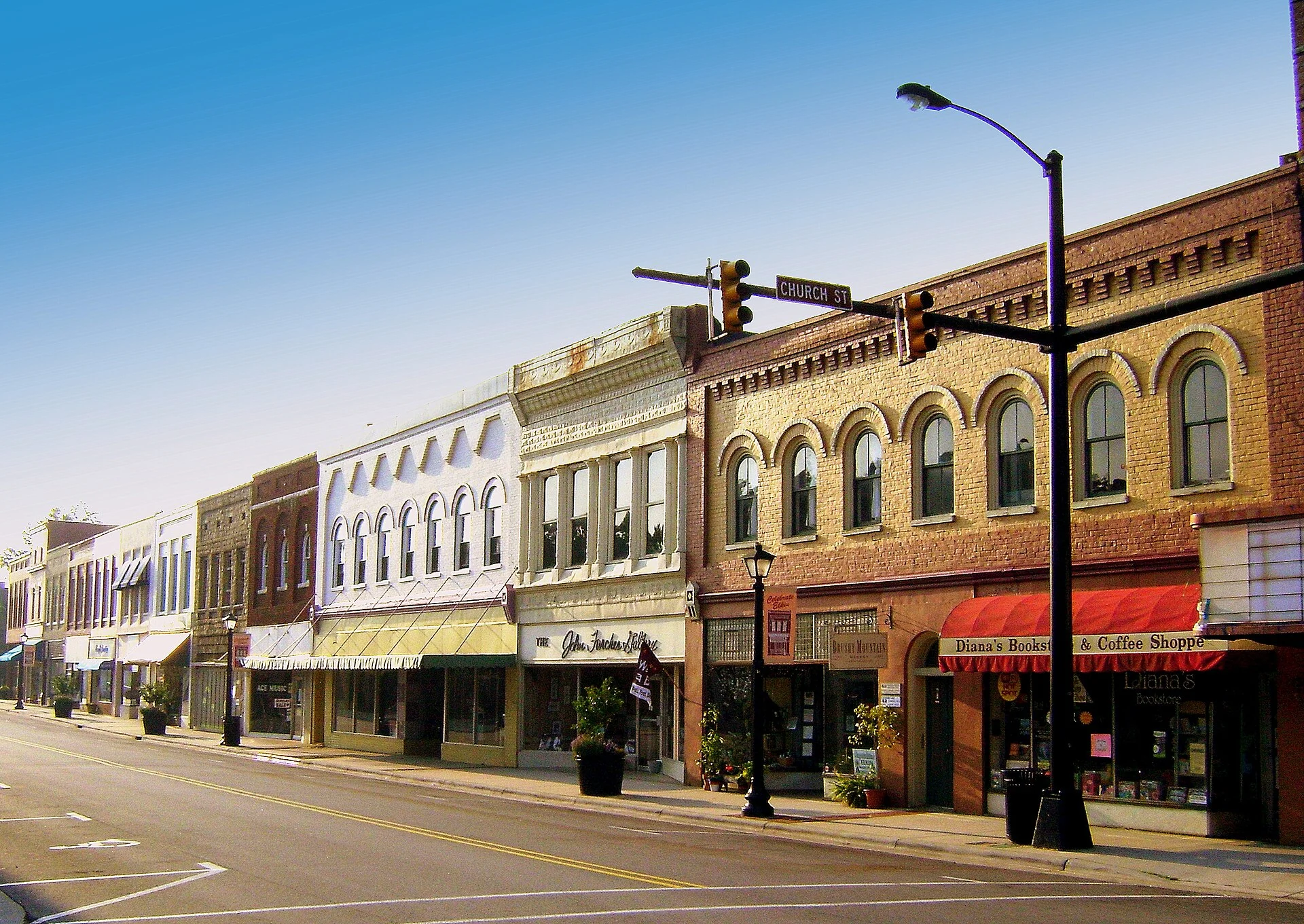 Two- and three-story brick storefronts with decorative cornices and awnings line a downtown Elkin street.