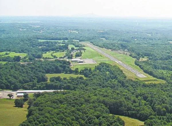 Aerial view of the Elkin Municipal Airport runway cutting through wooded hills and farmland.